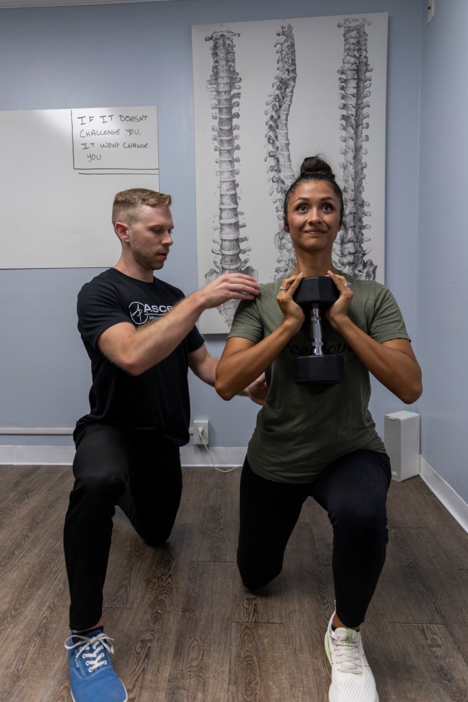 Dr. Jacob Tomlinson assisting a patient during a squat exercise for knee pain therapy at Ascend Physical Therapy