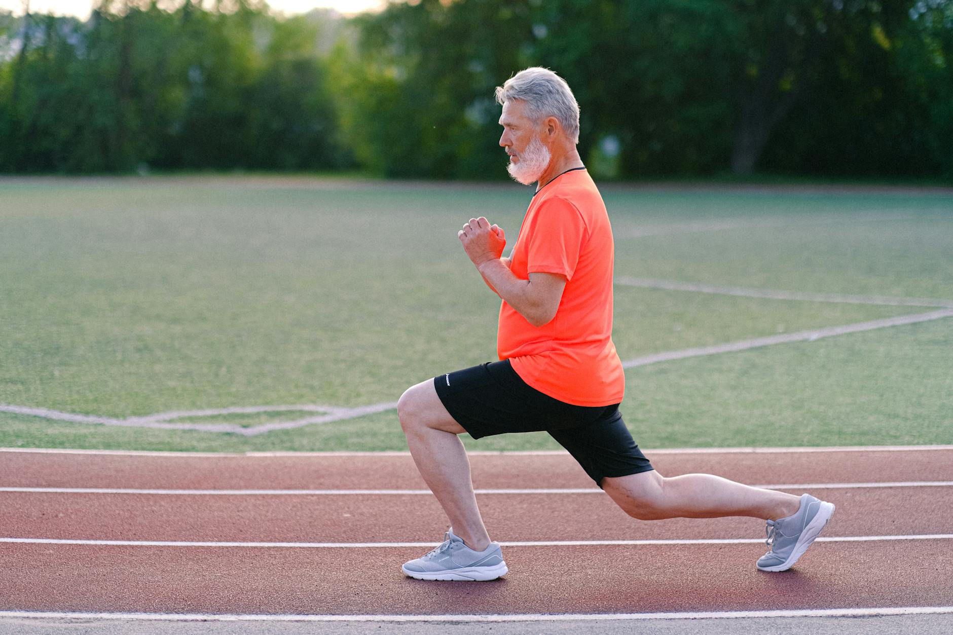 senior man in sportswear warming up on stadium